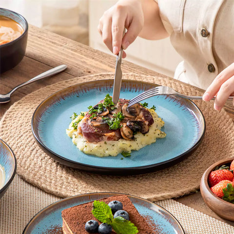 Assorted dishes with soup - dessert - and fruit salad on rustic wooden table - Amber 16-Piece blue stoneware dinnerware set with plates and bowls by vancasso