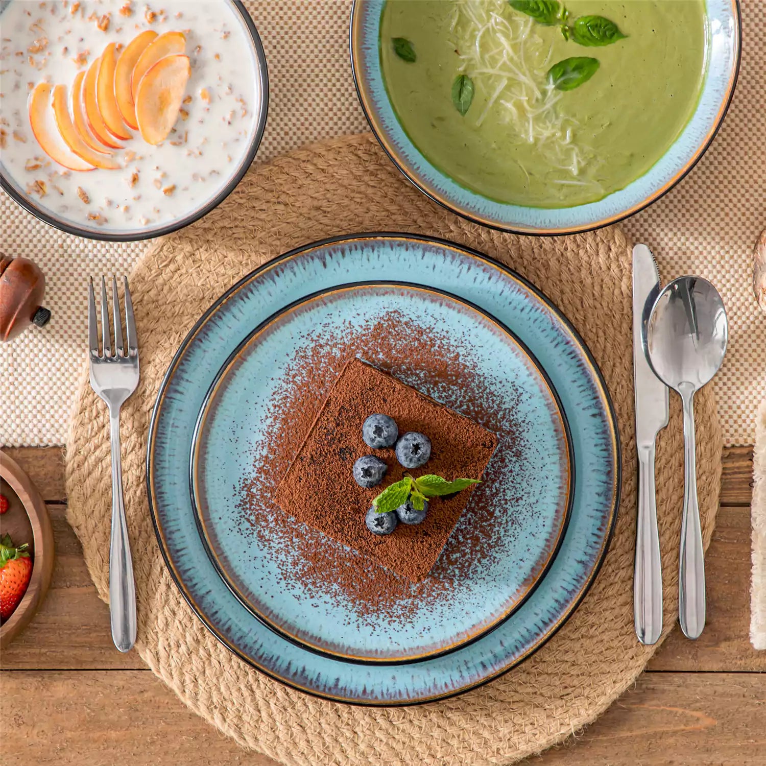 Assorted dishes with soup - dessert -  and fruit salad on rustic wooden table - Amber 16-Piece blue stoneware dinnerware set with plates and bowls by vancasso