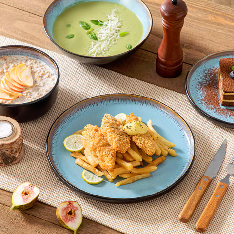 Assorted dishes with soup - dessert - and fruit salad on rustic wooden table - Amber 16-Piece blue stoneware dinnerware set with plates and bowls by vancasso