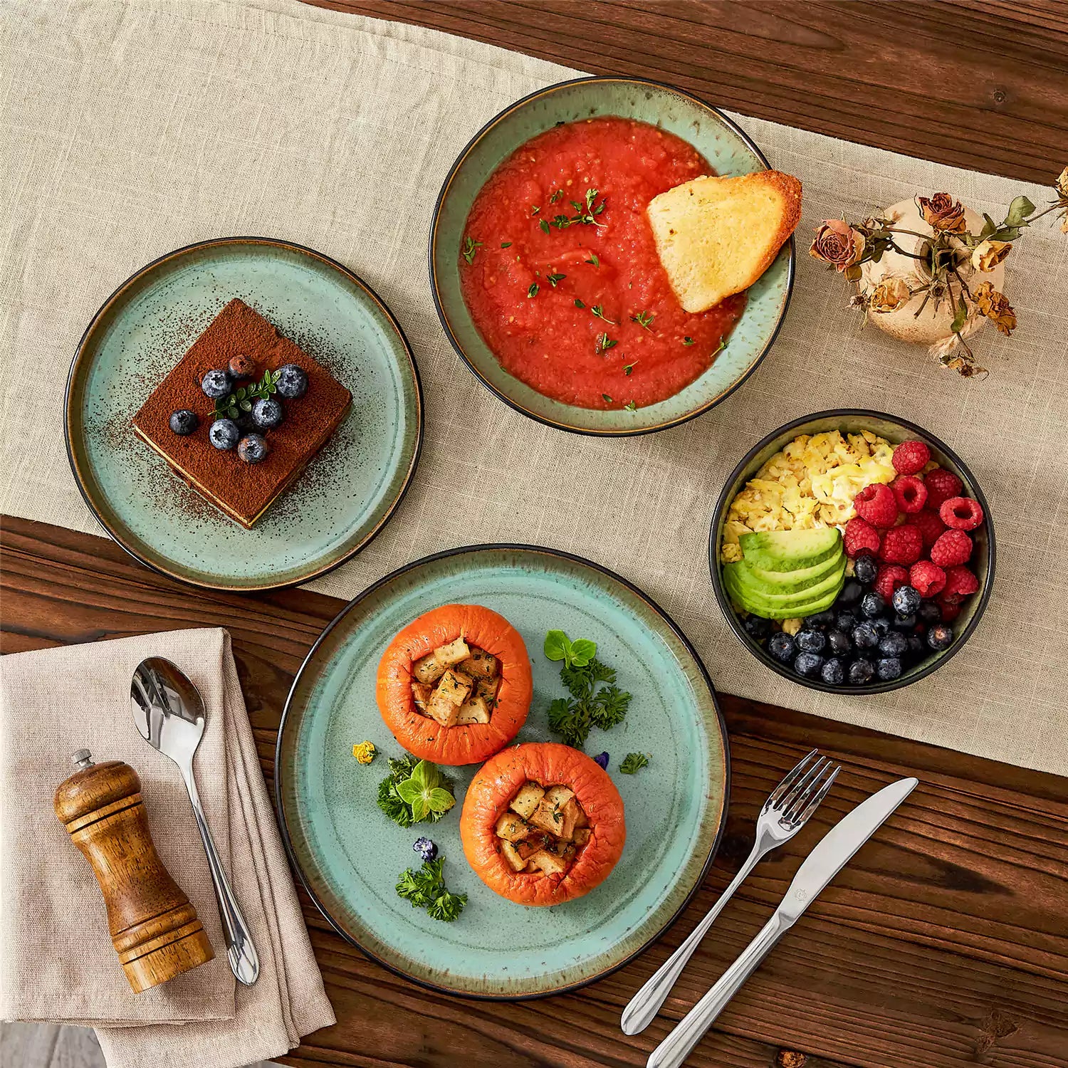 Assorted dishes with soup - dessert - and fruit salad on rustic wooden table - Amber 16-Piece green stoneware dinnerware set with plates and bowls by vancasso