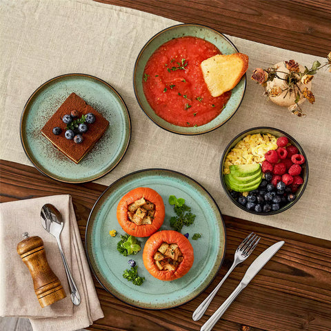 Assorted dishes with soup - dessert - and fruit salad on rustic wooden table - Amber 16-Piece green stoneware dinnerware set with plates and bowls by vancasso
