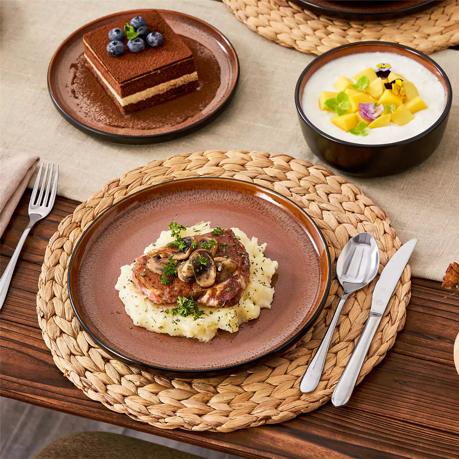 Rustic dining table with Amber 12-piece stoneware dinnerware in farmhouse red - featuring reactive glaze plates - bowls - and utensils by vancasso