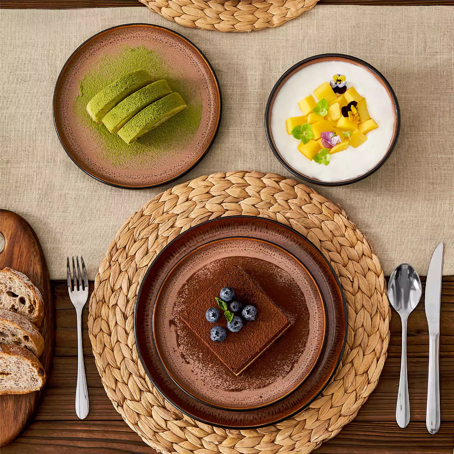 Assorted dishes with soup - dessert - and fruit salad on rustic wooden table - Amber 16-Piece red stoneware dinnerware set with plates and bowls by vancasso