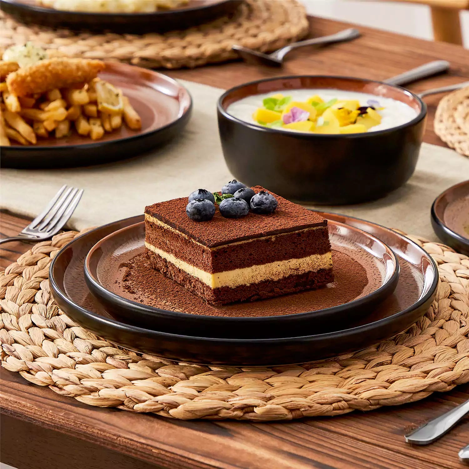 Assorted dishes with soup - dessert - and fruit salad on rustic wooden table - Amber 16-Piece red stoneware dinnerware set with plates and bowls by vancasso