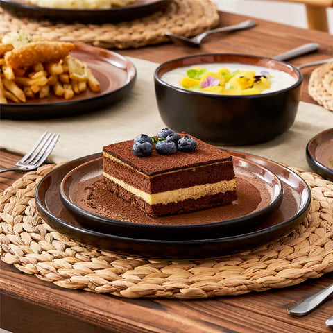 Assorted dishes with soup - dessert - and fruit salad on rustic wooden table - Amber 16-Piece red stoneware dinnerware set with plates and bowls by vancasso
