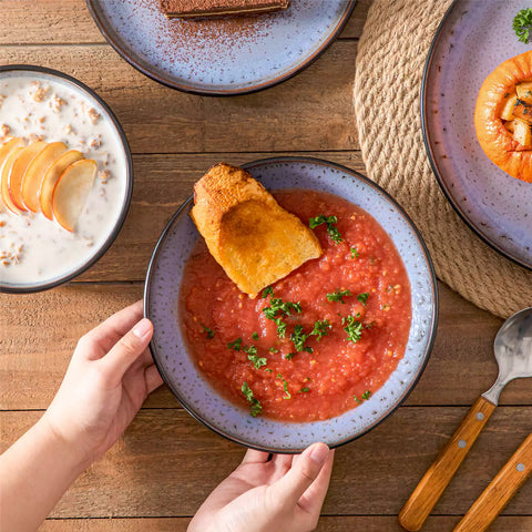 Assorted dishes with soup - dessert - and fruit salad on rustic wooden table - Amber 16-Piece violet stoneware dinnerware set with plates and bowls by vancasso