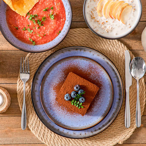 Assorted dishes with soup - dessert - and fruit salad on rustic wooden table - Amber 16-Piece violet stoneware dinnerware set with plates and bowls by vancasso