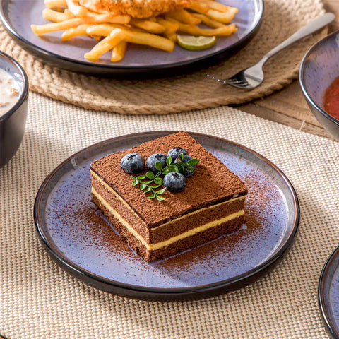 Assorted dishes with soup - dessert - and fruit salad on rustic wooden table - Amber 16-Piece violet stoneware dinnerware set with plates and bowls by vancasso