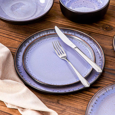 Assorted dishes with soup - dessert - and fruit salad on rustic wooden table - Amber 16-Piece violet stoneware dinnerware set with plates and bowls by vancasso
