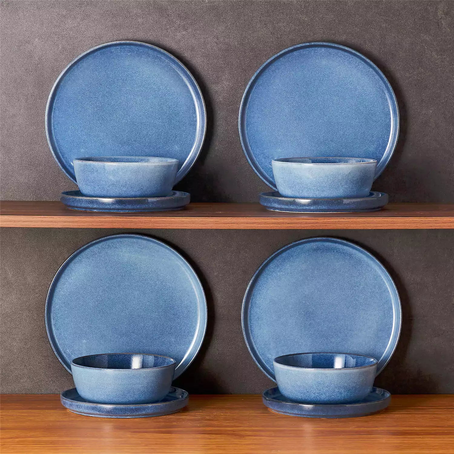 Blue stoneware plates and bowls with reactive glaze on farmhouse wooden table with woven placemats