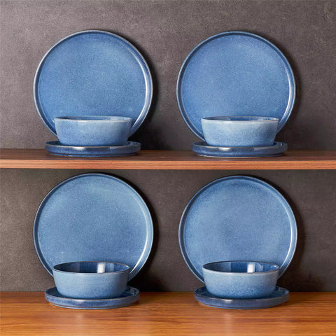 Blue stoneware plates and bowls with reactive glaze on farmhouse wooden table with woven placemats