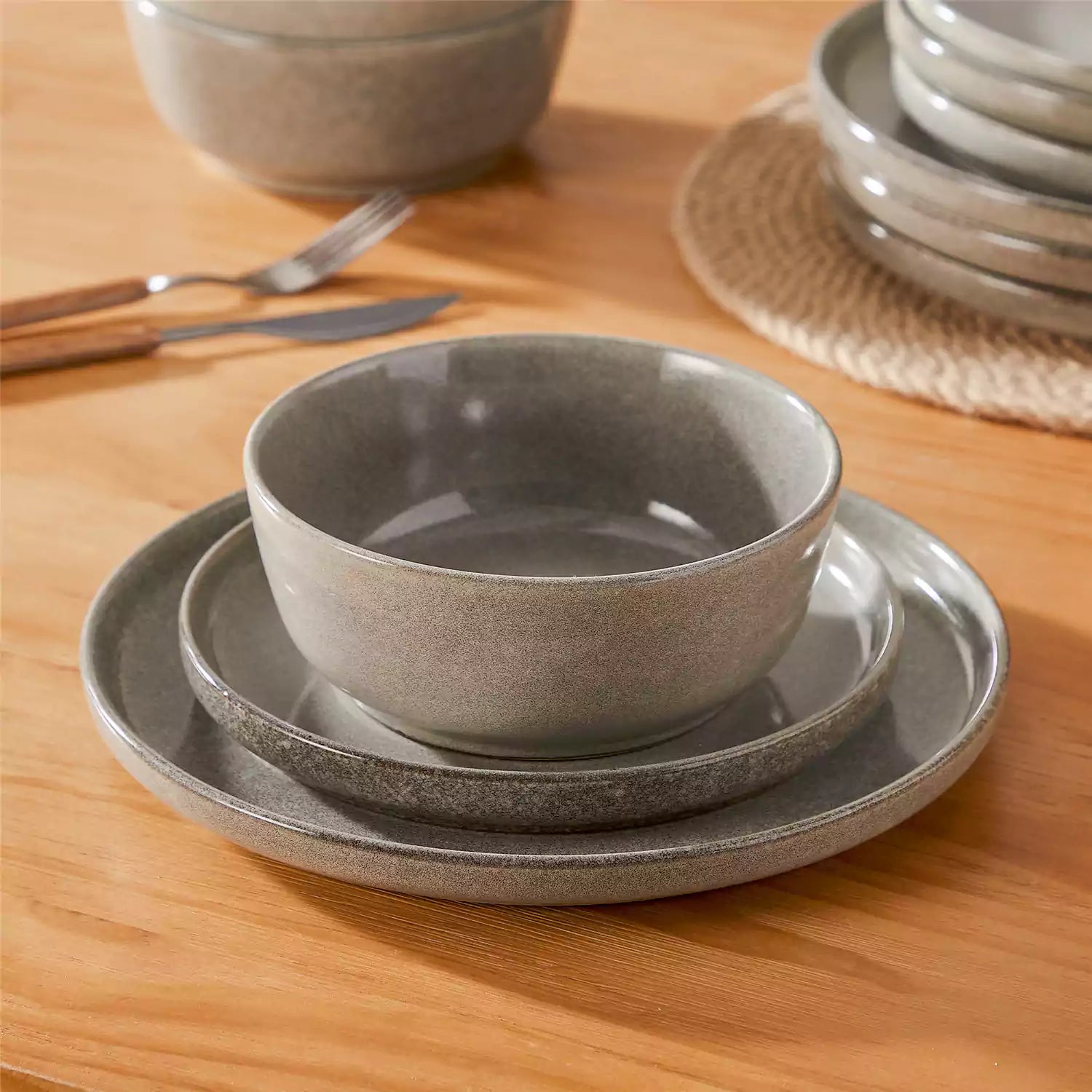 Brown stoneware plates and bowls with reactive glaze on farmhouse wooden table with woven placemats