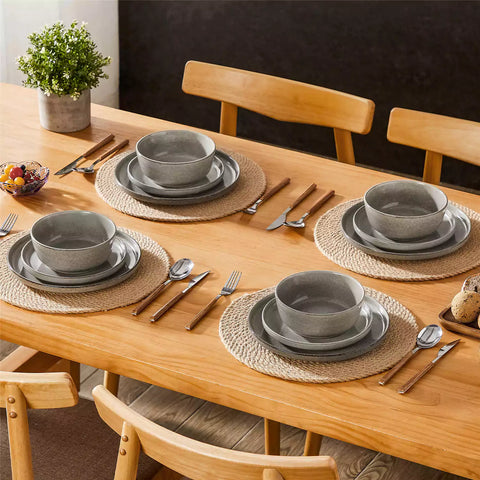 Brown stoneware plates and bowls with reactive glaze on farmhouse wooden table with woven placemats