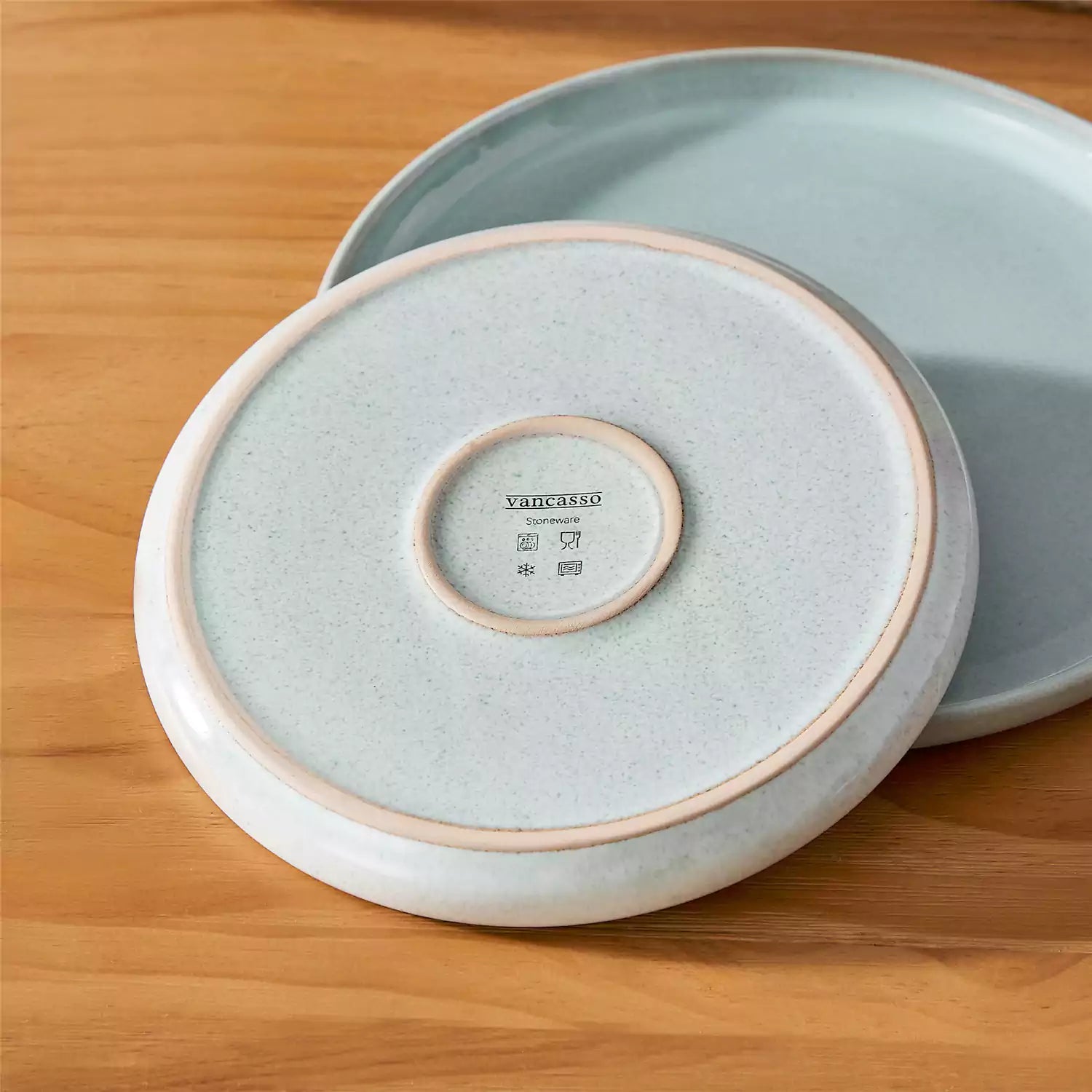 Mint green stoneware plates and bowls with reactive glaze on farmhouse wooden table with woven placemats