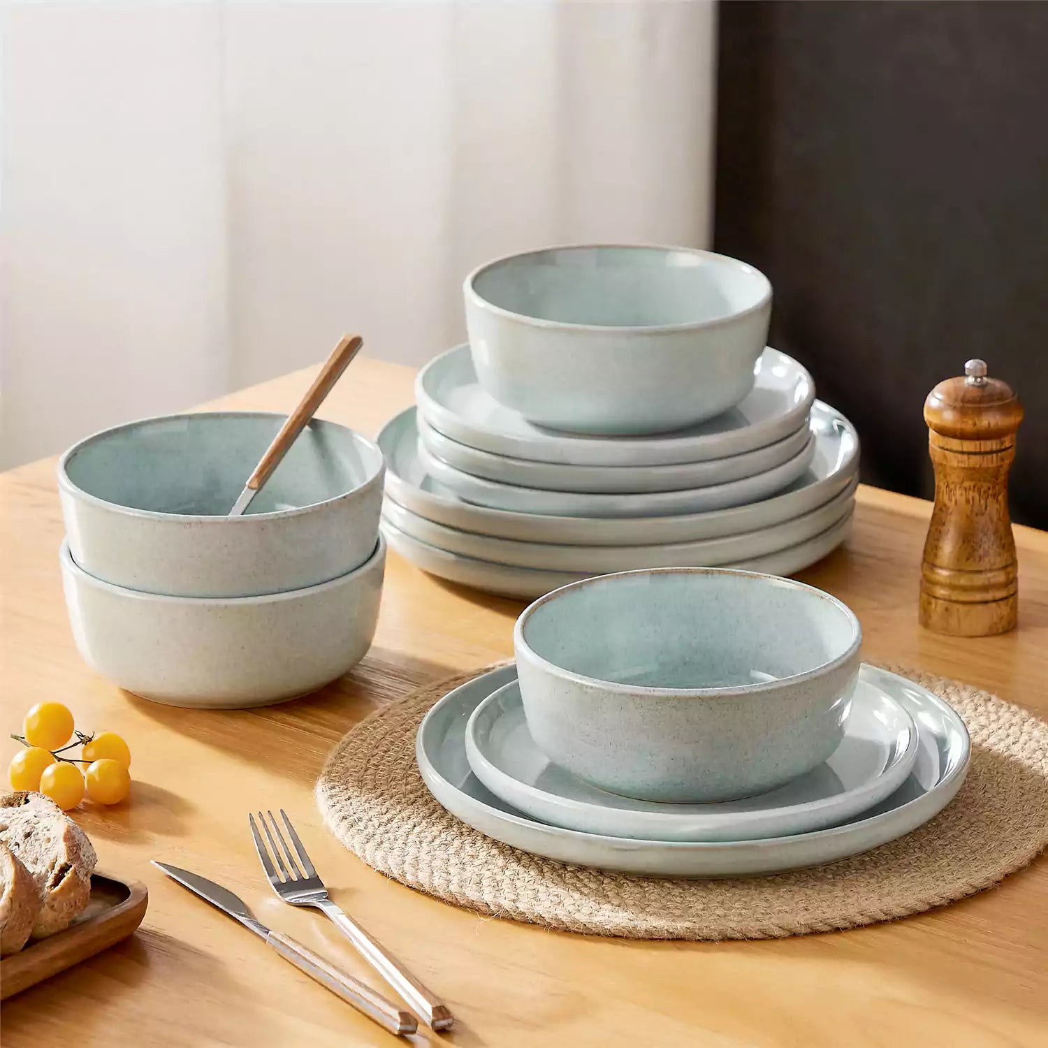 Mint green stoneware plates and bowls with reactive glaze on farmhouse wooden table with woven placemats