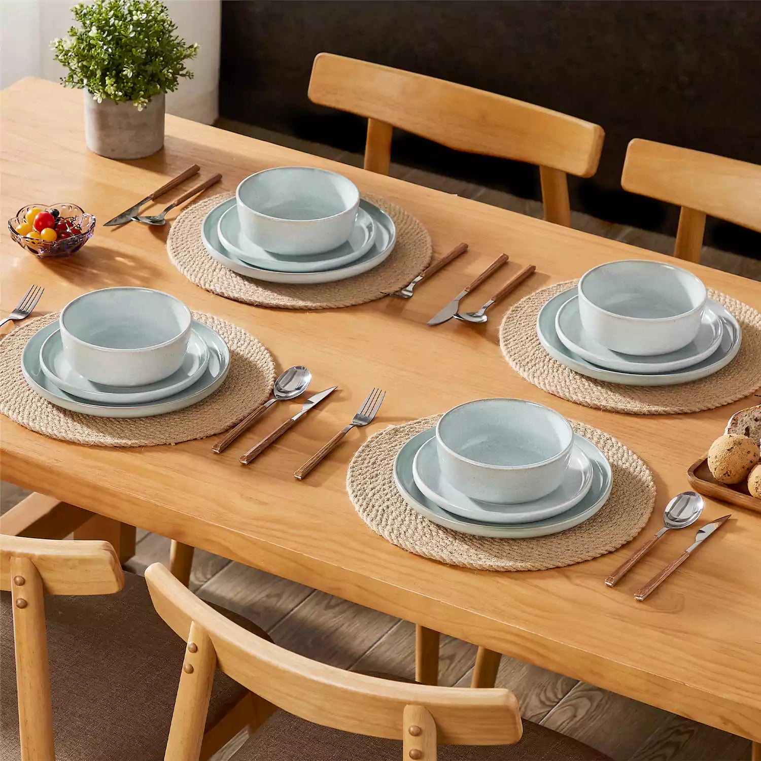 Mint green stoneware plates and bowls with reactive glaze on farmhouse wooden table with woven placemats