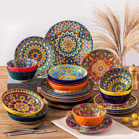 Lumi 24 piece porcelain dinnerware set with vibrant patterns stacked on a wooden table with colorful placemats and assorted dishes