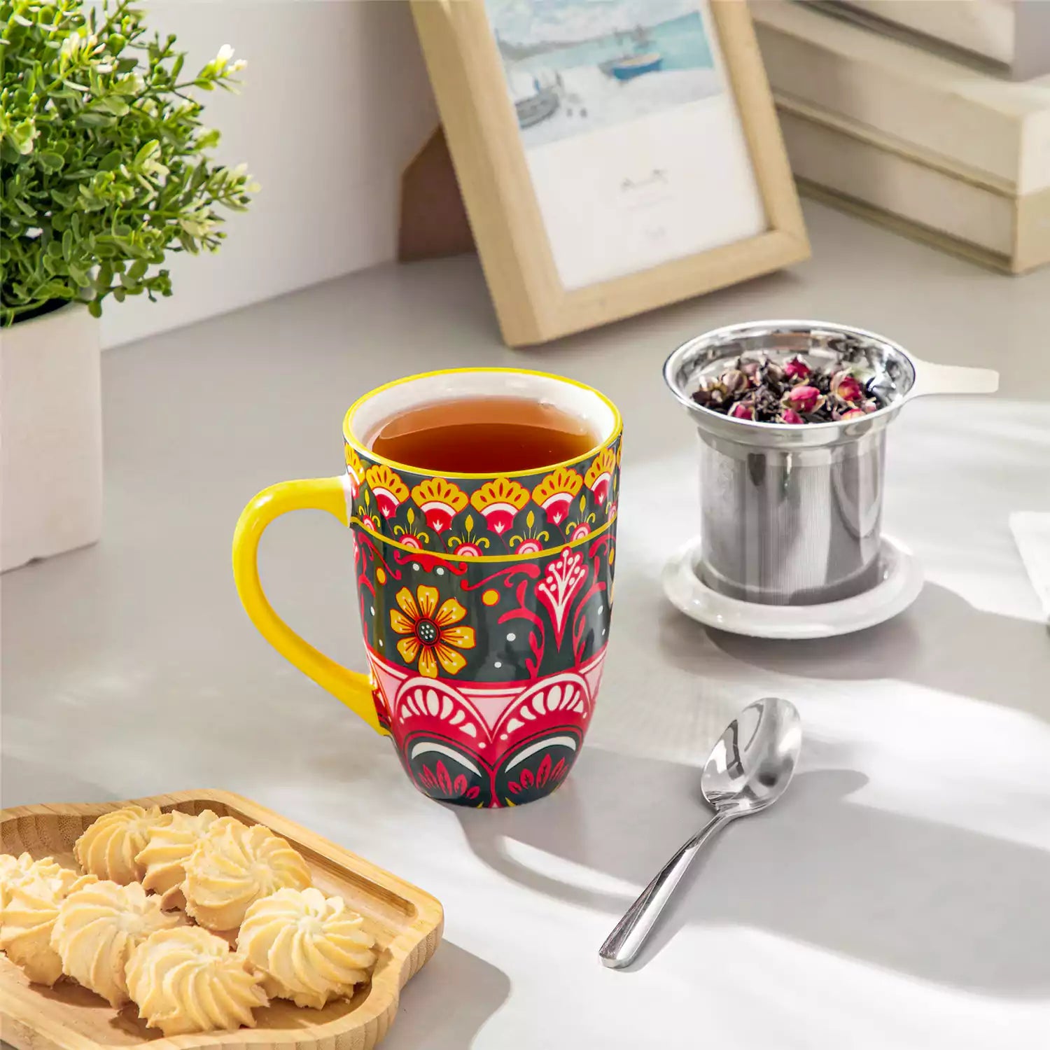 Lumi lemon yellow porcelain tea mug with infuser and lid featuring vibrant Bohemian pattern on a wooden desk with laptop and plant