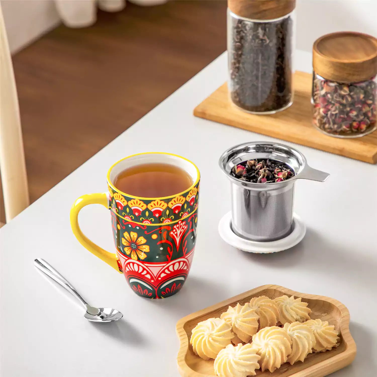 Lumi lemon yellow porcelain tea mug with infuser and lid featuring vibrant Bohemian pattern on a wooden desk with laptop and plant
