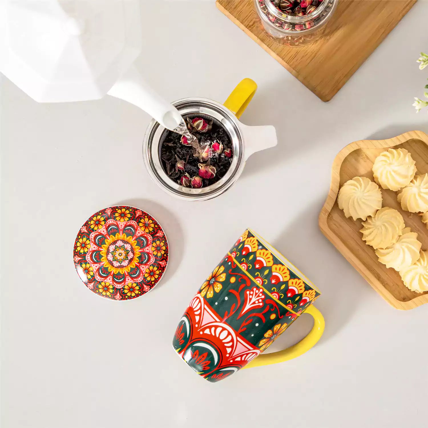 Lumi lemon yellow porcelain tea mug with infuser and lid featuring vibrant Bohemian pattern on a wooden desk with laptop and plant