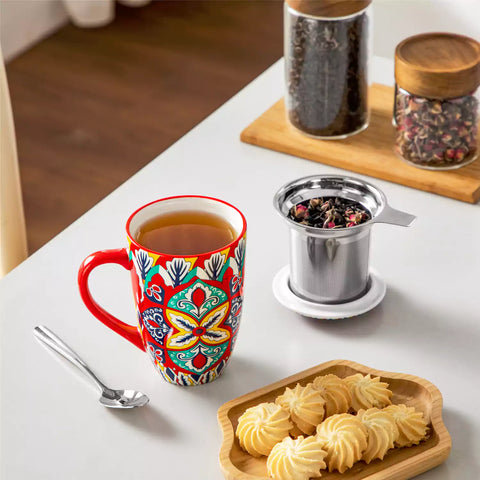 Lumi flame red porcelain tea mug with infuser and lid featuring vibrant Bohemian pattern on a wooden desk with laptop and plant