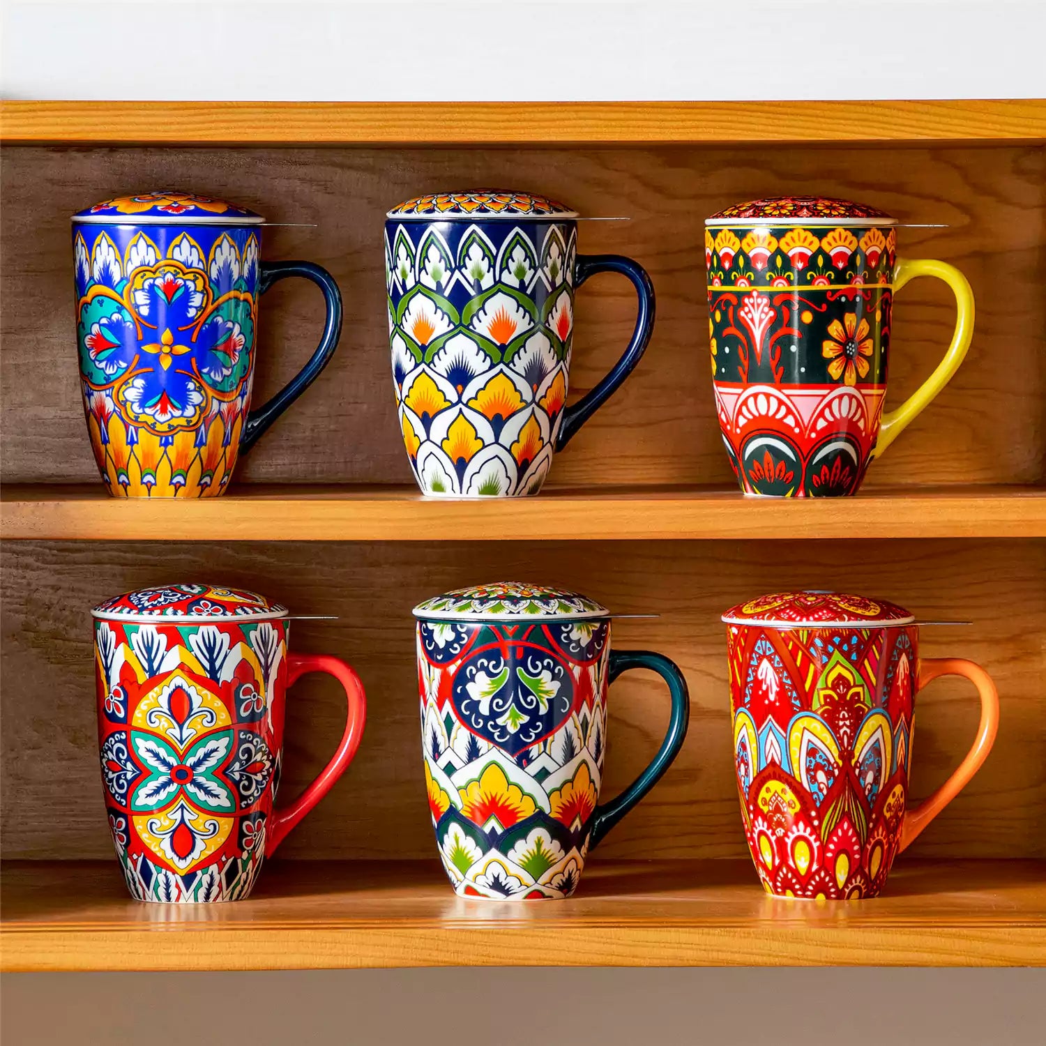 Lumi flame red porcelain tea mug with infuser and lid featuring vibrant Bohemian pattern on a wooden desk with laptop and plant