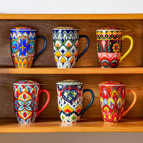 Lumi flame red porcelain tea mug with infuser and lid featuring vibrant Bohemian pattern on a wooden desk with laptop and plant