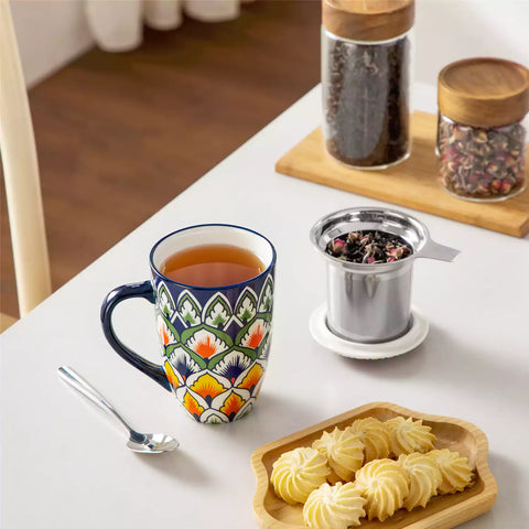 Lumi hunter green porcelain tea mug with infuser and lid featuring vibrant Bohemian pattern on a wooden desk with laptop and plant