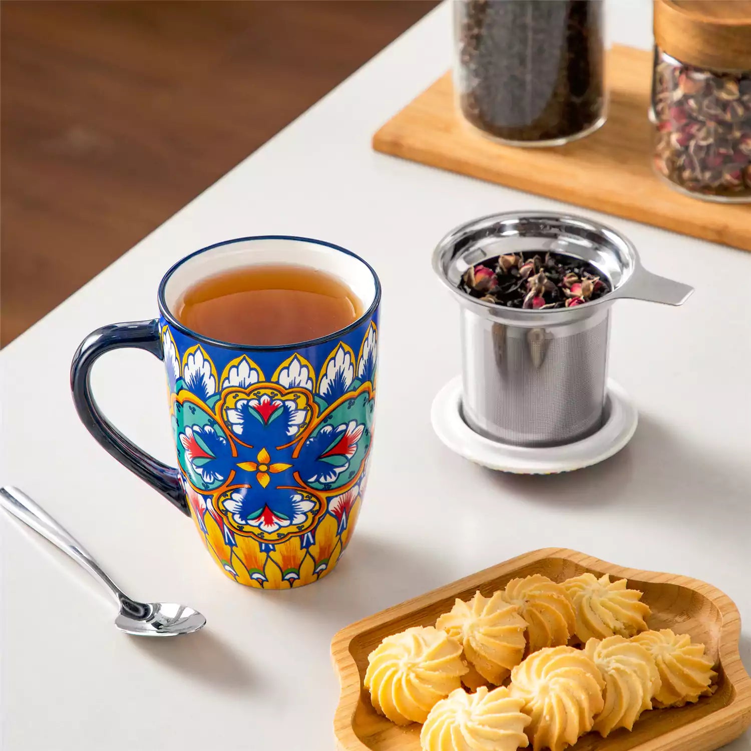 Lumi vibrant blue porcelain tea mug with infuser and lid featuring vibrant Bohemian pattern on a wooden desk with laptop and plant