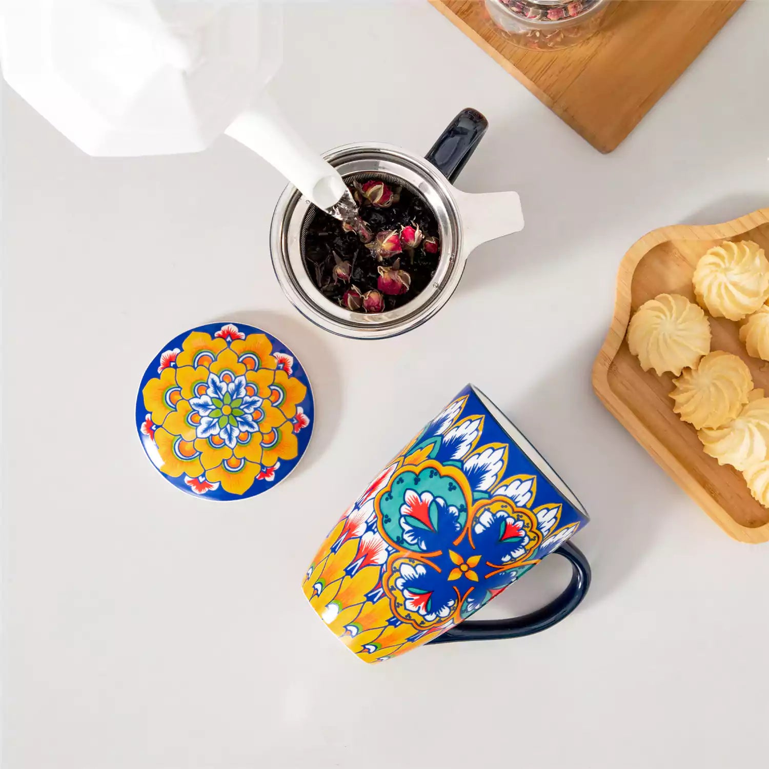 Lumi vibrant blue porcelain tea mug with infuser and lid featuring vibrant Bohemian pattern on a wooden desk with laptop and plant