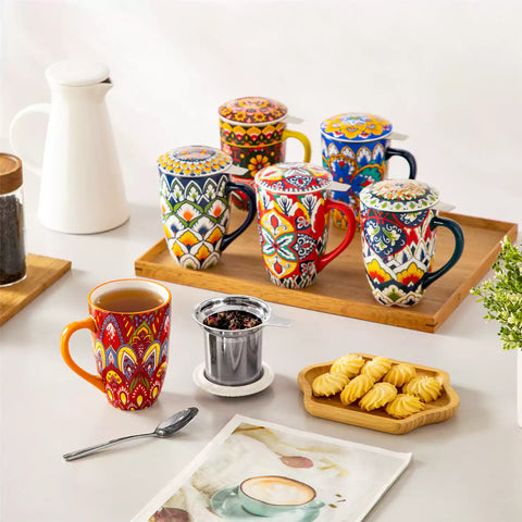 Lumi bold orange porcelain tea mug with infuser and lid featuring vibrant Bohemian pattern on a wooden desk with laptop and plant