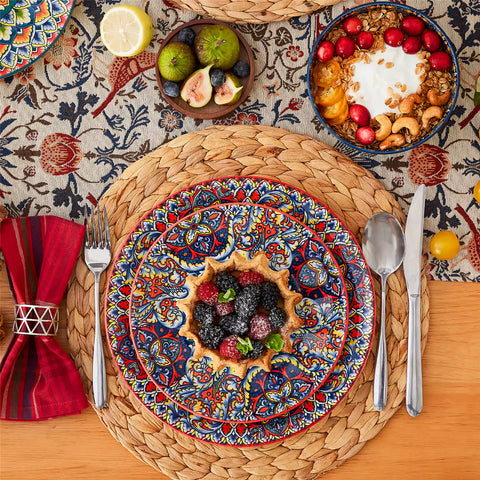 Lumi 18-piece Bohemian dinnerware set for six on a wooden table with colorful plates bowls and silverware in a playful Boho style