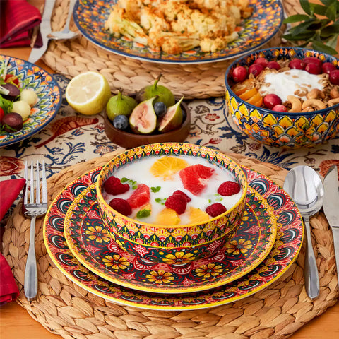 Lumi 18-piece Bohemian dinnerware set for six on a wooden table with colorful plates bowls and silverware in a playful Boho style