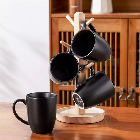 Playa set of four black stoneware mugs and a classic Moka pot on a wooden tray with a morning brew beside fresh pastries and coffee beans 