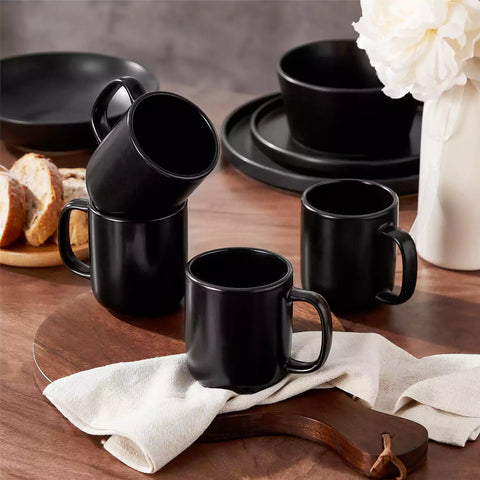 Playa 12oz stoneware mug in solid matte black on a rustic wooden surface for a moody coffee break with spoon and scattered beans