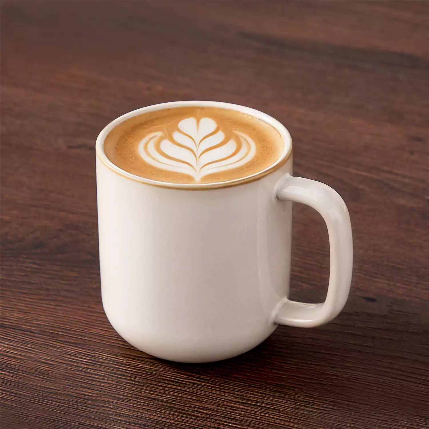 Playa 16oz stoneware mugs in beige reactive glaze on a rustic wooden café table with coffee maker and pastries