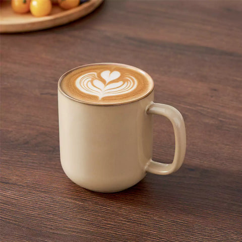 Playa 16oz stoneware mugs in brown reactive glaze on a rustic wooden café table with coffee maker and pastries