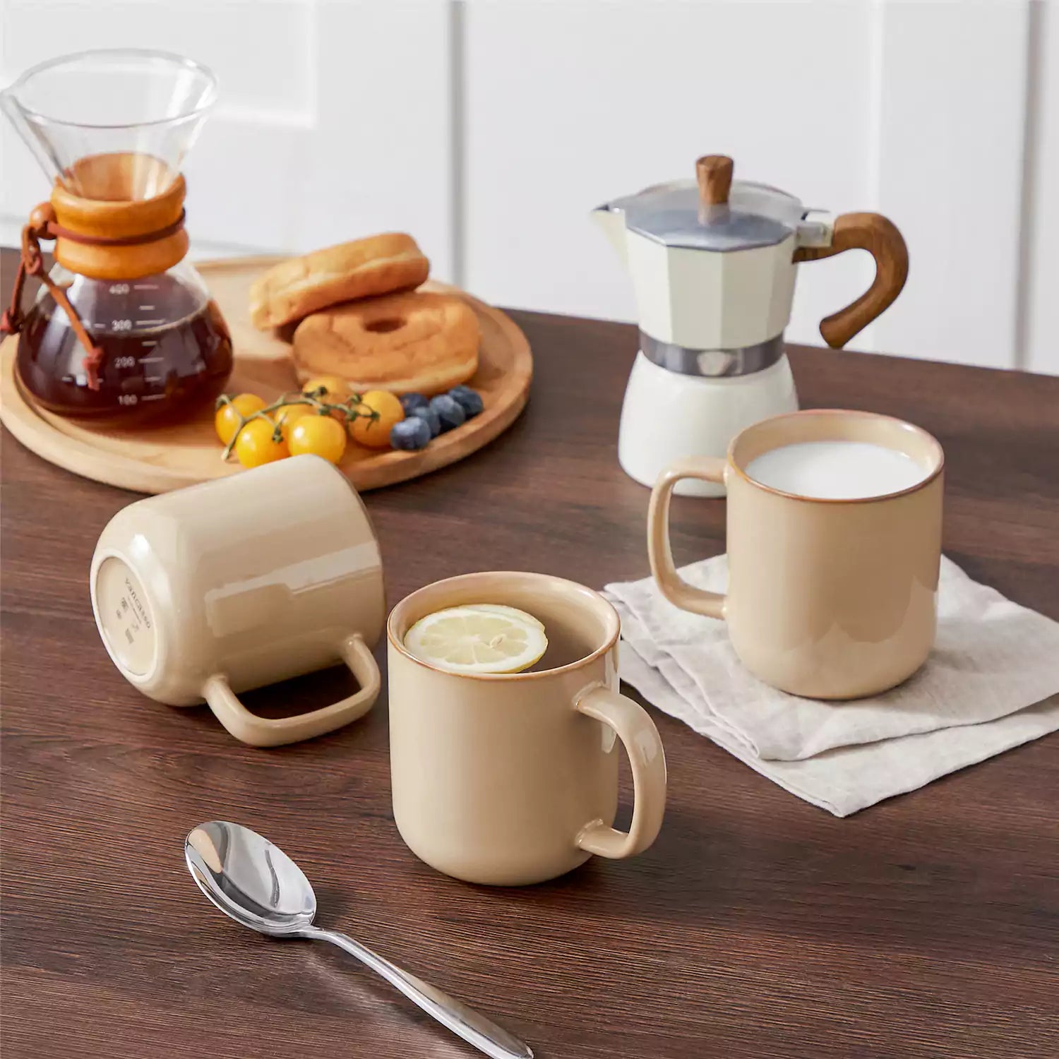 Playa 16oz stoneware mugs in brown reactive glaze on a rustic wooden café table with coffee maker and pastries