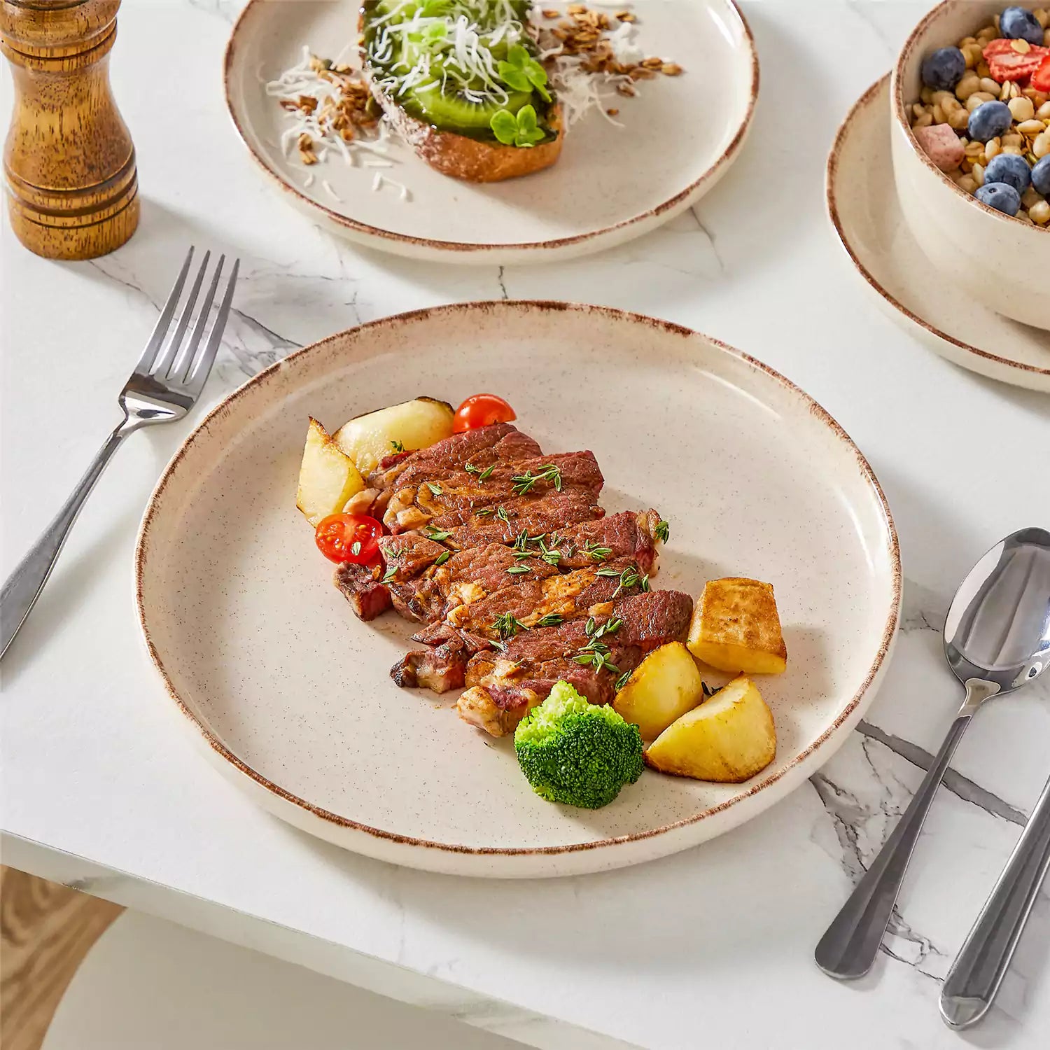 Plays 18-piece stoneware dinnerware set with steak and vegetables on marble table - featuring sandy speckled plates and bowls with brown rims-vancasso