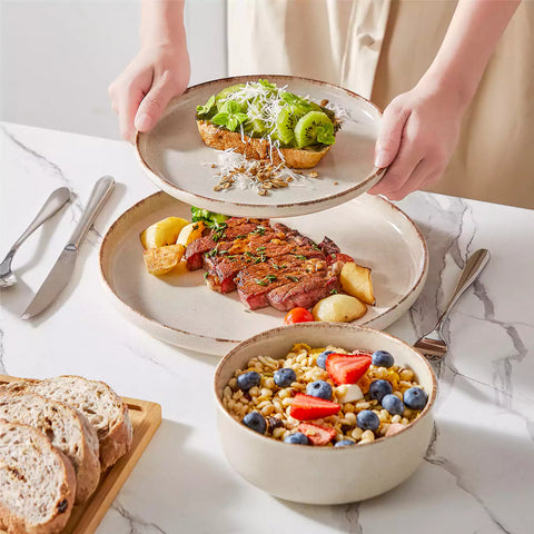 Plays 18-piece stoneware dinnerware set with steak and vegetables on marble table - featuring sandy speckled plates and bowls with brown rims-vancasso