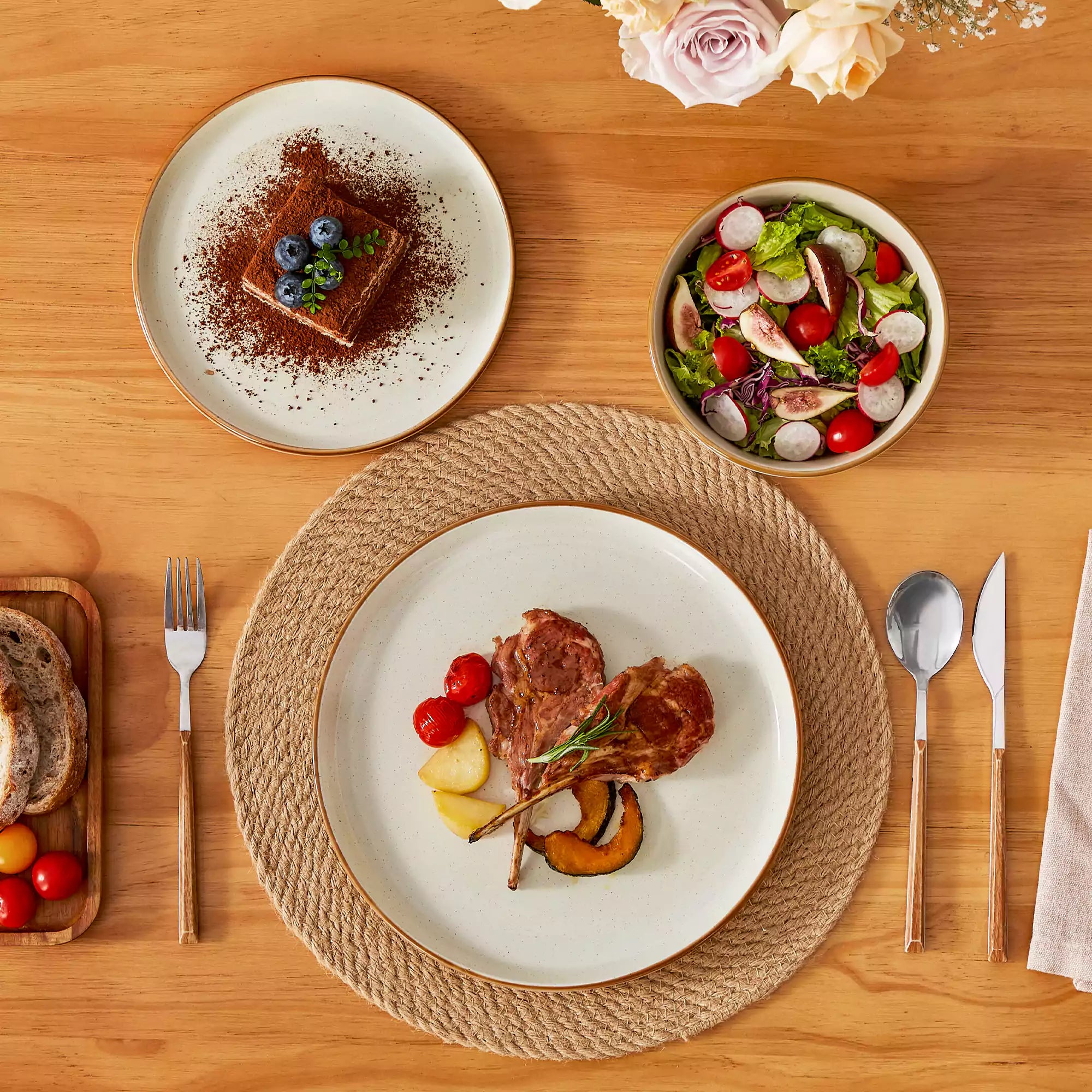 Beige rustic stoneware dinnerware set with speckled - lipped-edge plates and bowls on a dining table with flowers and cutlery in a cozy modern kitchen-vancasso
