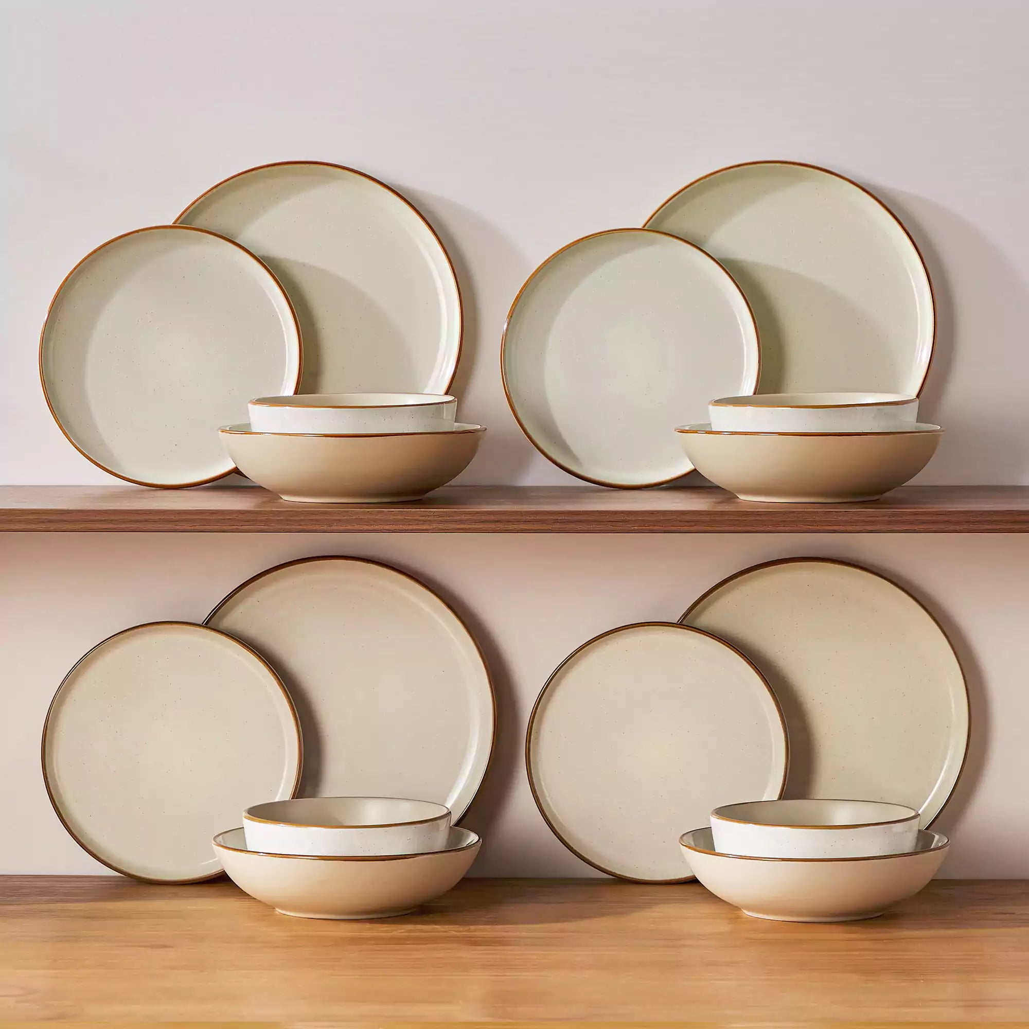 Rustic beige speckled stoneware dinnerware set with lipped-edge plates and bowls arranged on a sunlit modern dining table-vancasso
