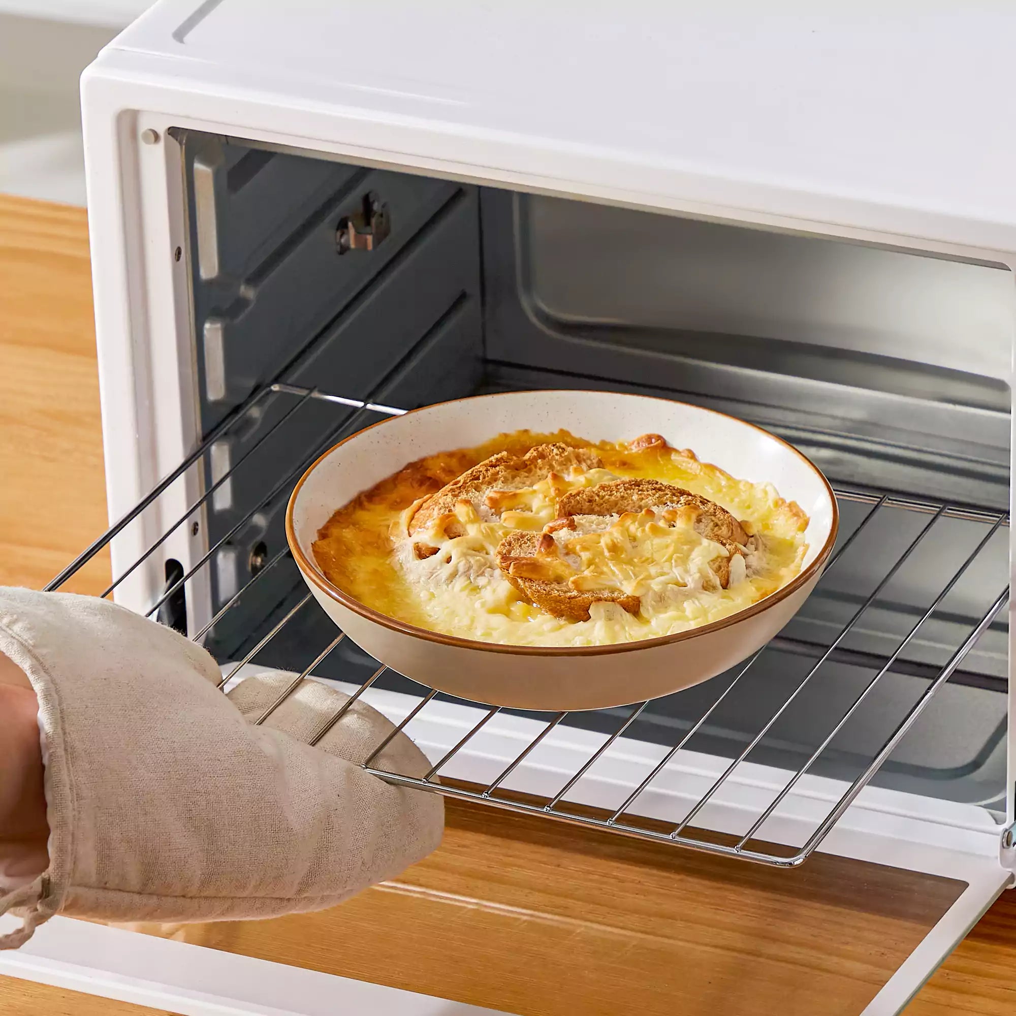 Rustic beige speckled stoneware dinnerware set with lipped-edge plates and bowls arranged on a sunlit modern dining table-vancasso