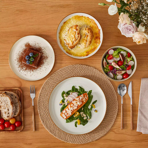Rustic beige speckled stoneware dinnerware set with lipped-edge plates and bowls arranged on a sunlit modern dining table-vancasso