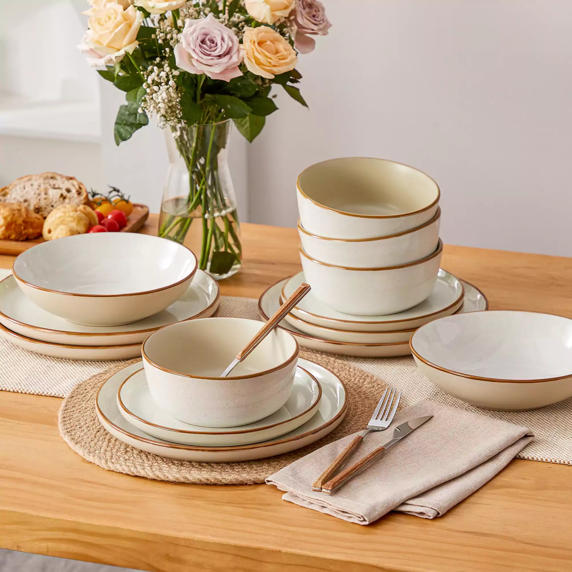 Rustic beige speckled stoneware dinnerware set with lipped-edge plates and bowls arranged on a sunlit modern dining table-vancasso