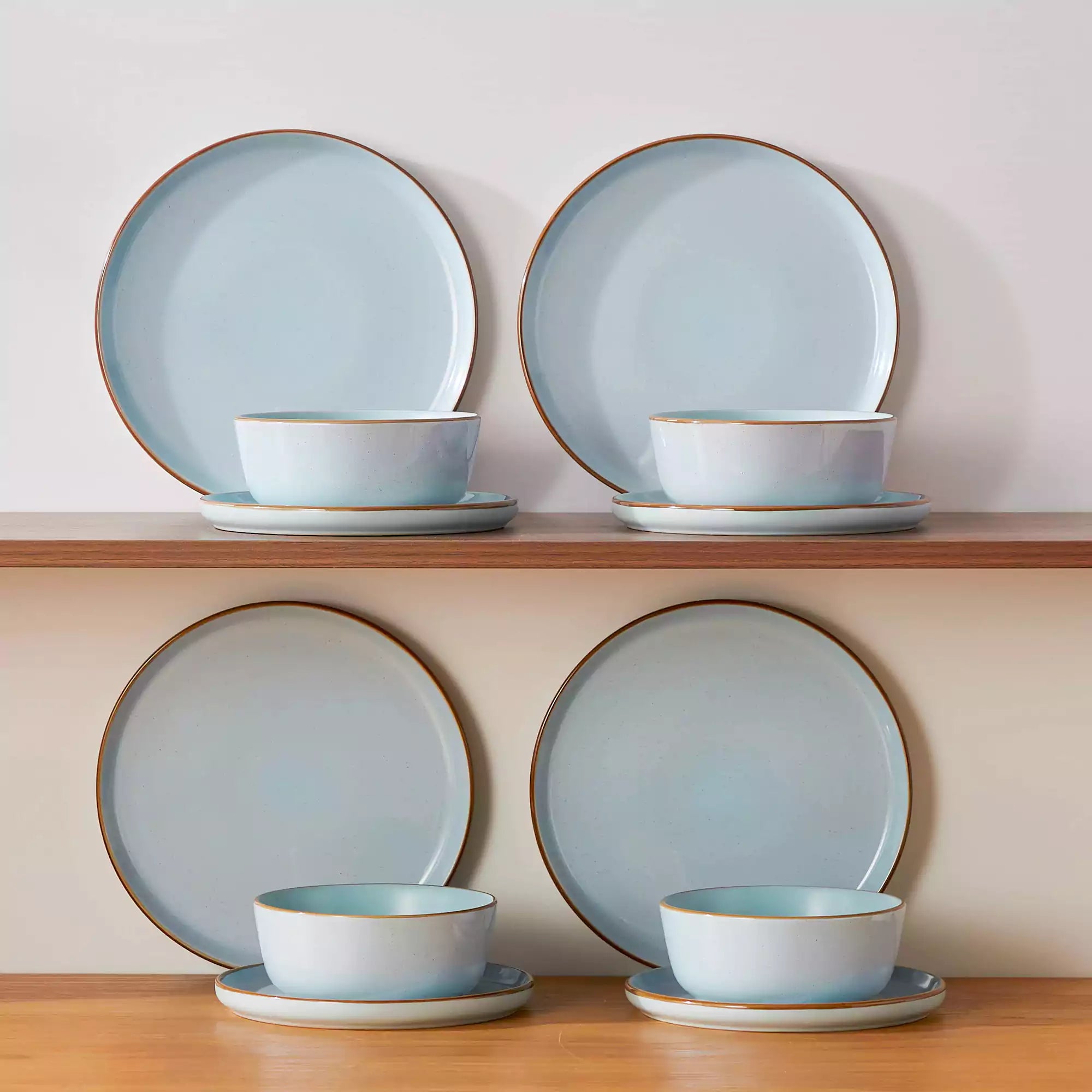 Blue rustic stoneware dinnerware set with speckled - lipped-edge plates and bowls on a dining table with flowers and cutlery in a cozy modern kitchen-vancasso