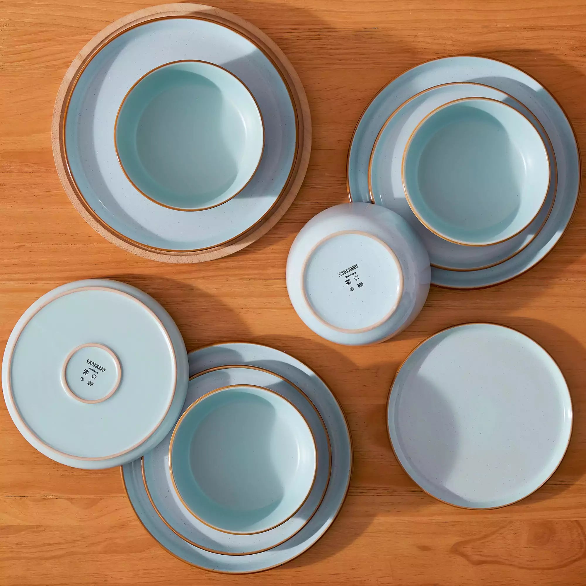 Blue rustic stoneware dinnerware set with speckled - lipped-edge plates and bowls on a dining table with flowers and cutlery in a cozy modern kitchen-vancasso