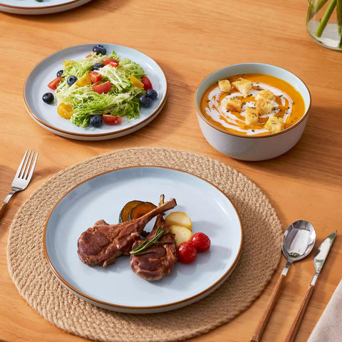Blue rustic stoneware dinnerware set with speckled - lipped-edge plates and bowls on a dining table with flowers and cutlery in a cozy modern kitchen-vancasso