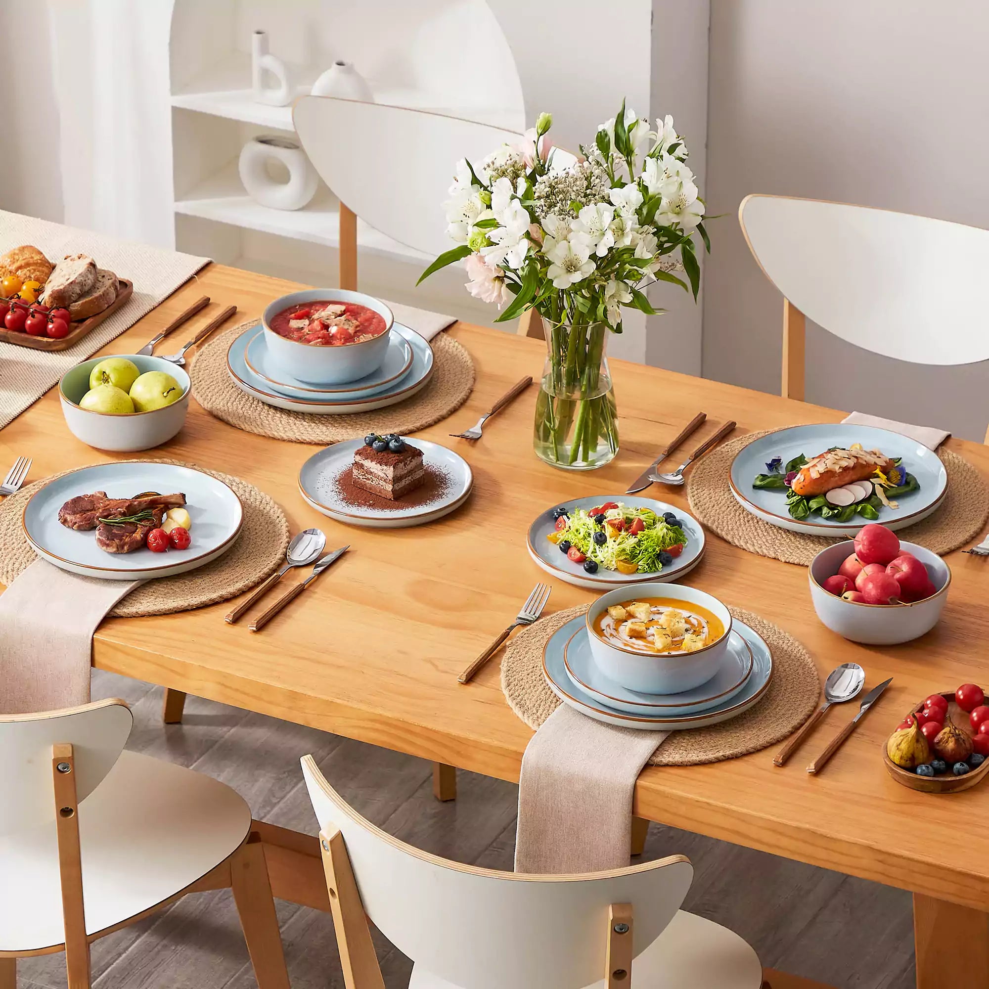 Blue rustic stoneware dinnerware set with speckled - lipped-edge plates and bowls on a dining table with flowers and cutlery in a cozy modern kitchen-vancasso