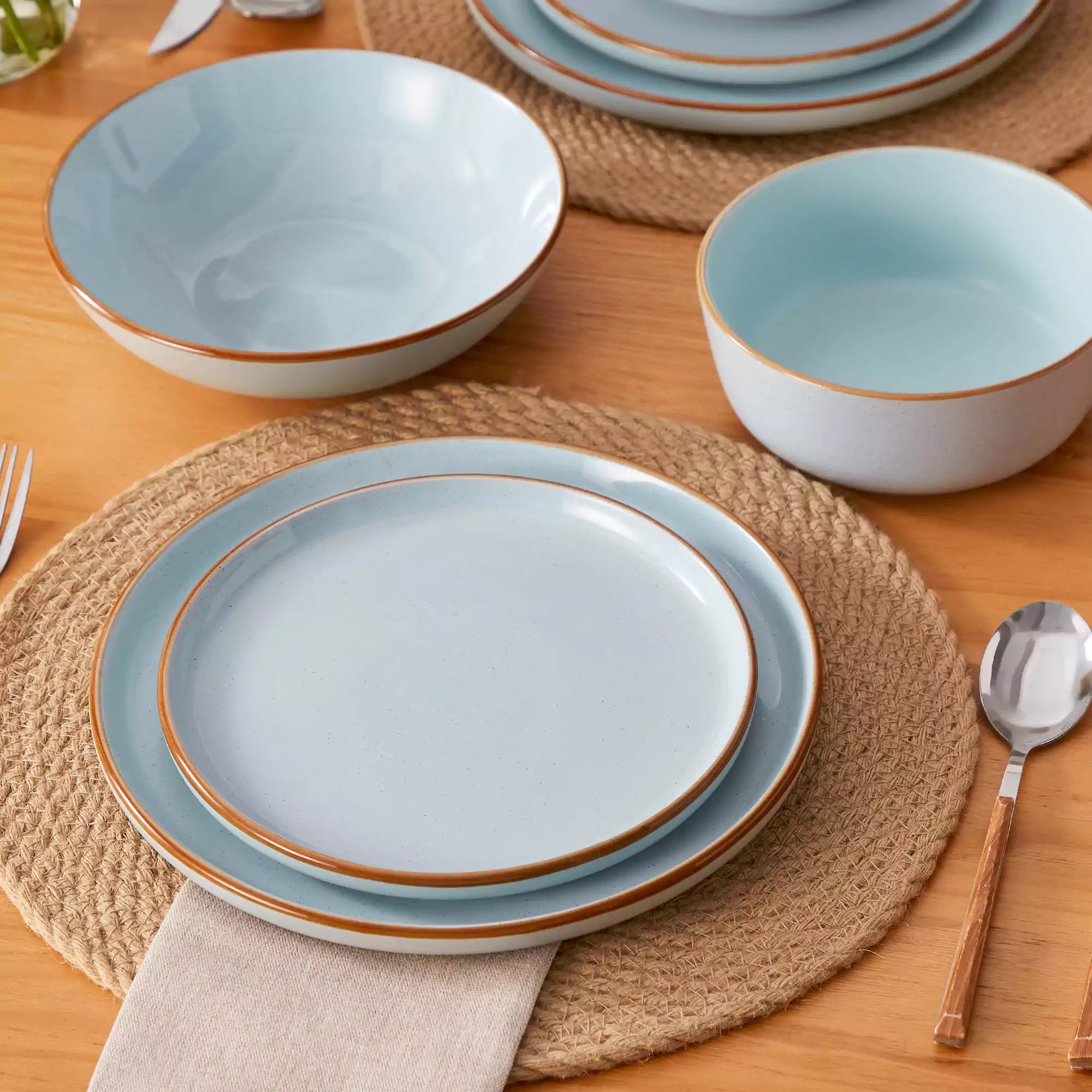 Rustic blue speckled stoneware dinnerware set with lipped-edge plates and bowls arranged on a sunlit modern dining table-vancasso